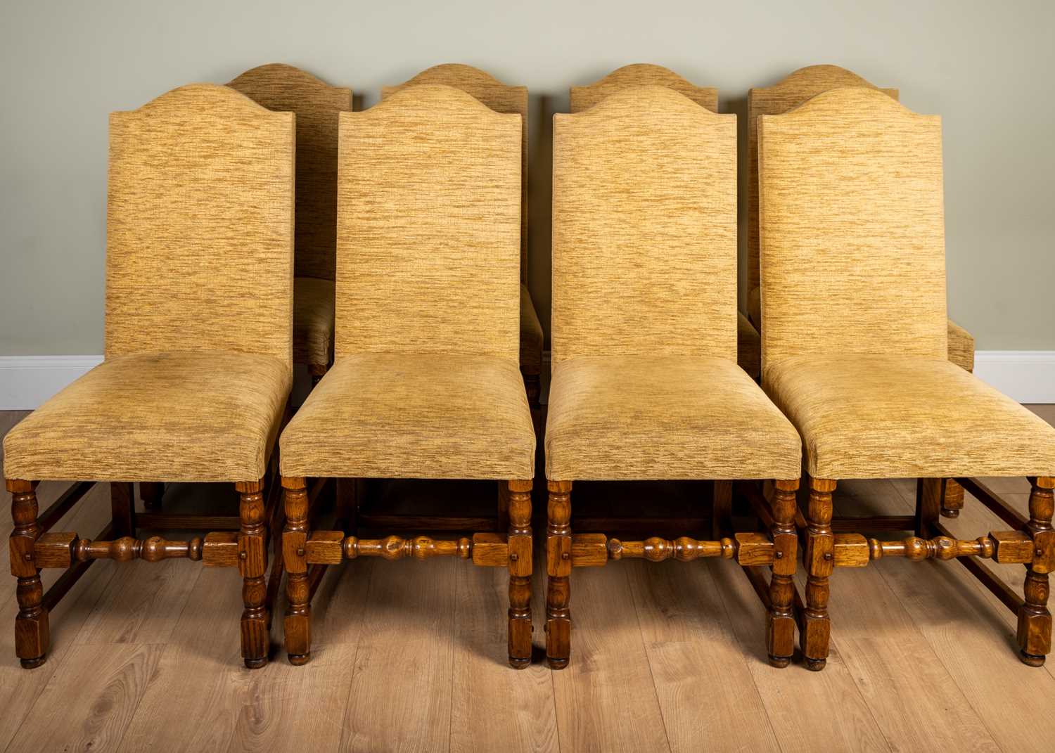 A set of eight high back dining chairs with upholstered seats and backs, on oak frame and turned