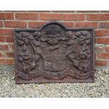 A cast iron fire back with arching top and decorated with central coat of arms flanked by heraldic