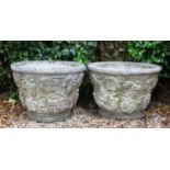 A pair of cast reconstituted stone conical garden planters decorated with fruiting vines, each