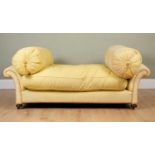 A yellow upholstered low sofa with scrolling arms on bun feet, with large, tasselled barrel