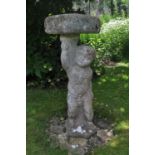 A reconstituted stone bird bath in the form of a scantily clad cherub holding aloft the bath, 82cm