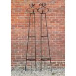 A pair of wrought iron spreading triangular section rose supports, with scrolling finials, each