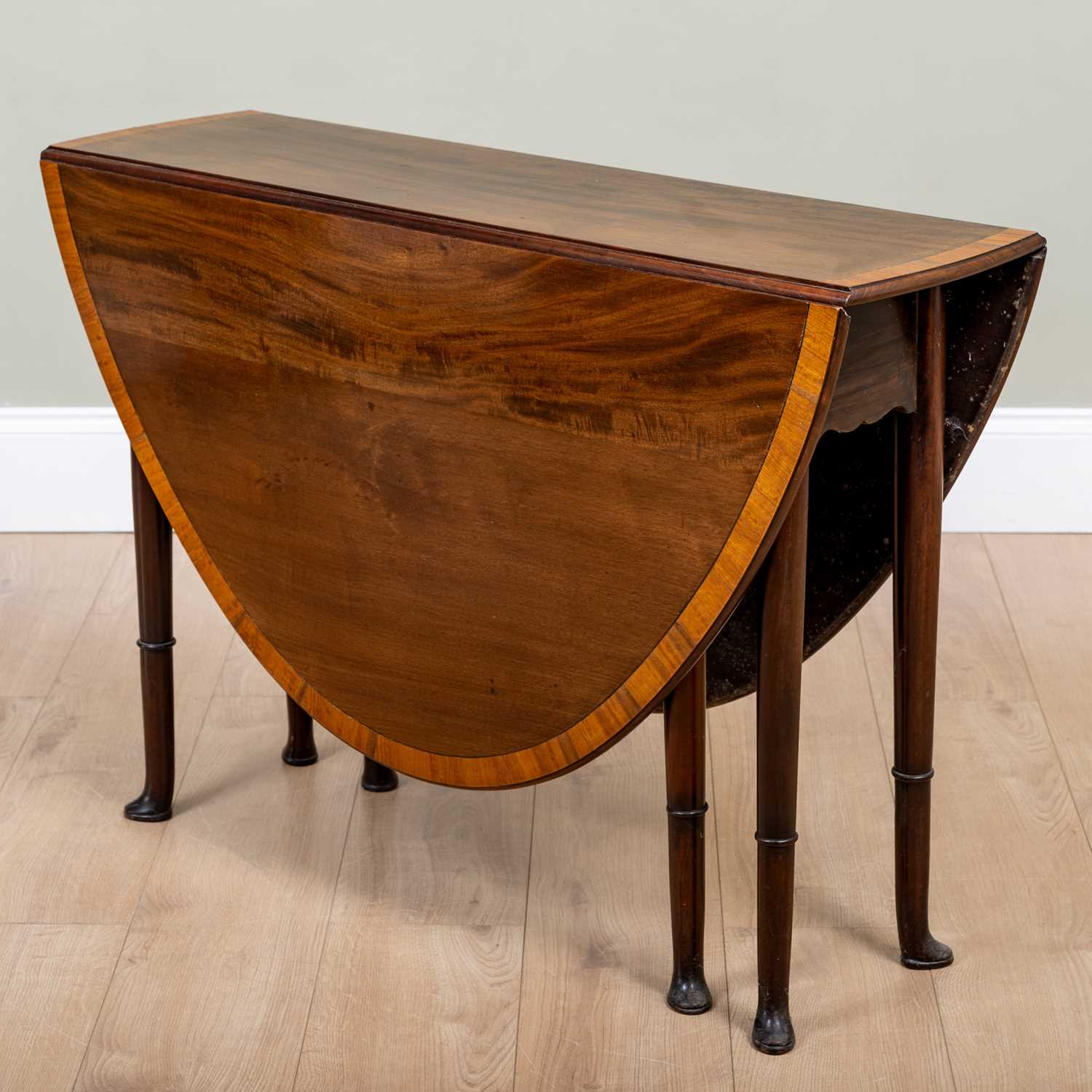 A 19th century mahogany drop leaf oval table with satinwood cross banded ornament and ring turned