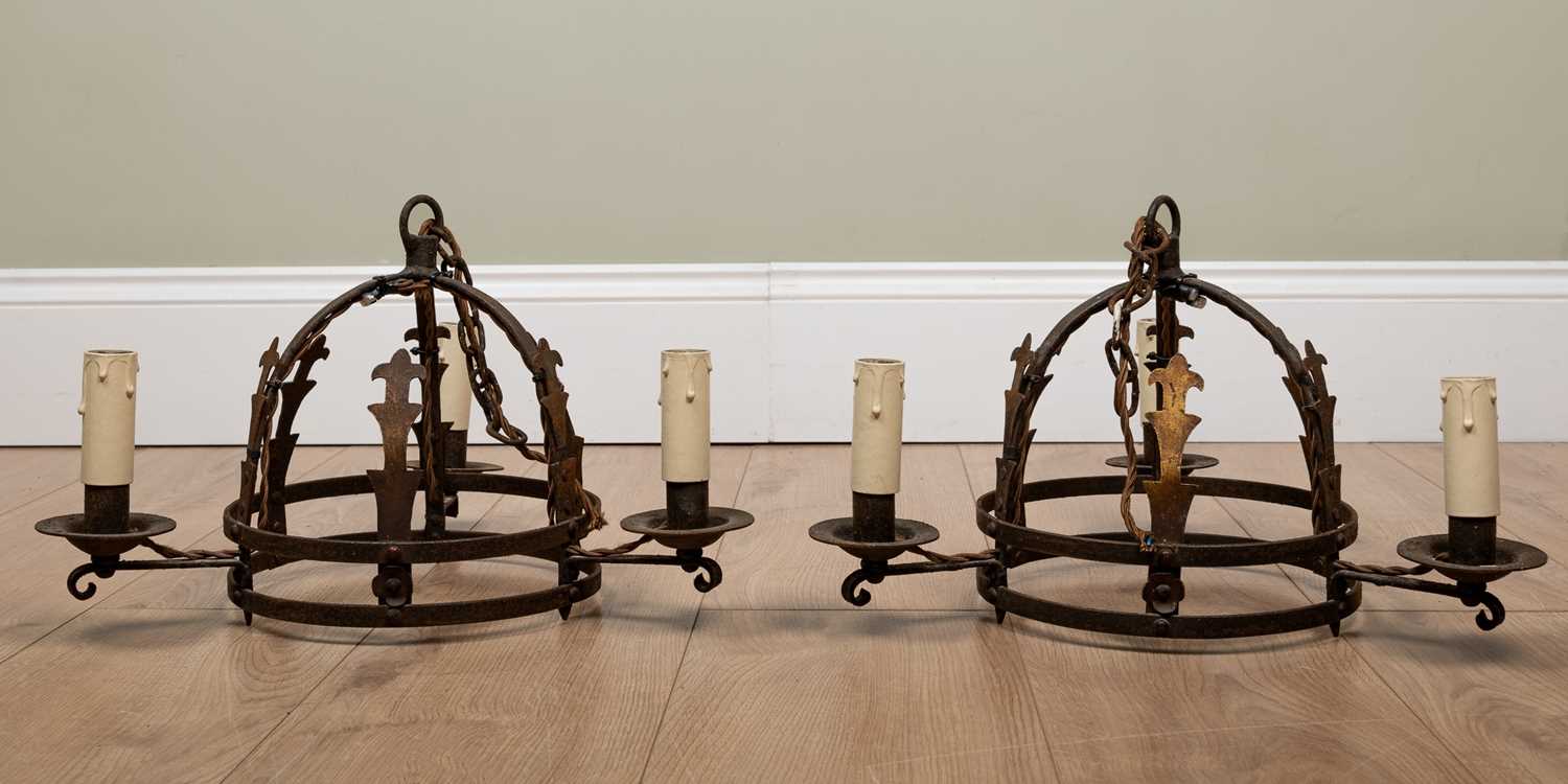 A pair of old wrought iron hanging light fittings, each with three branches and each approximately