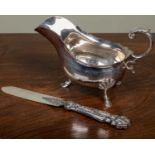 A Walker and Hall silver sauce boat, with scroll handle and hoof feet, 18cm long overall and 275.8