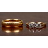 A 22ct gold wedding band together with a three stone diamond ring, the wedding band 5.7 grams in
