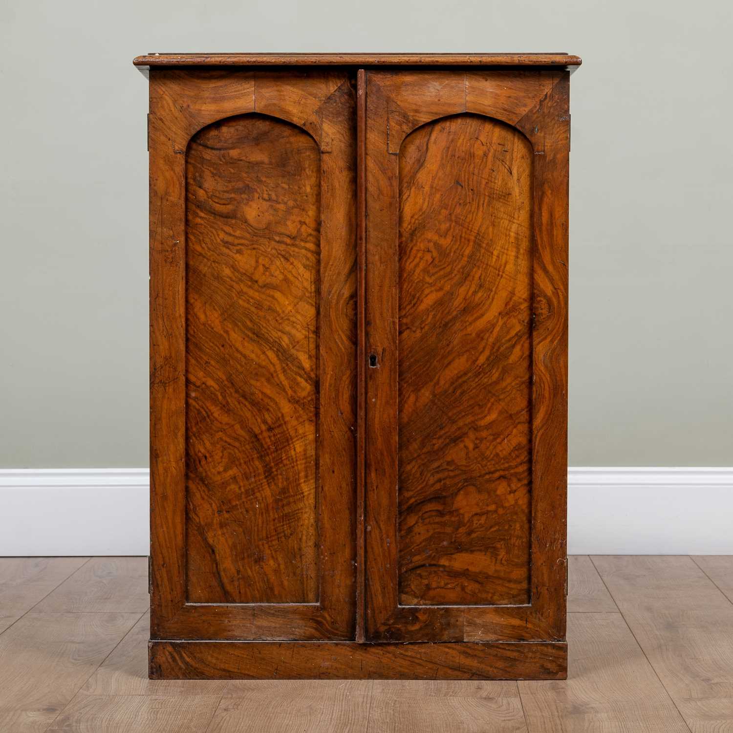 A 19th century walnut small cupboard with panelled doors enclosing adjustable shelves, with carrying