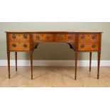 An early 19th century mahogany serpentine serving table with two short drawers to the centre above a
