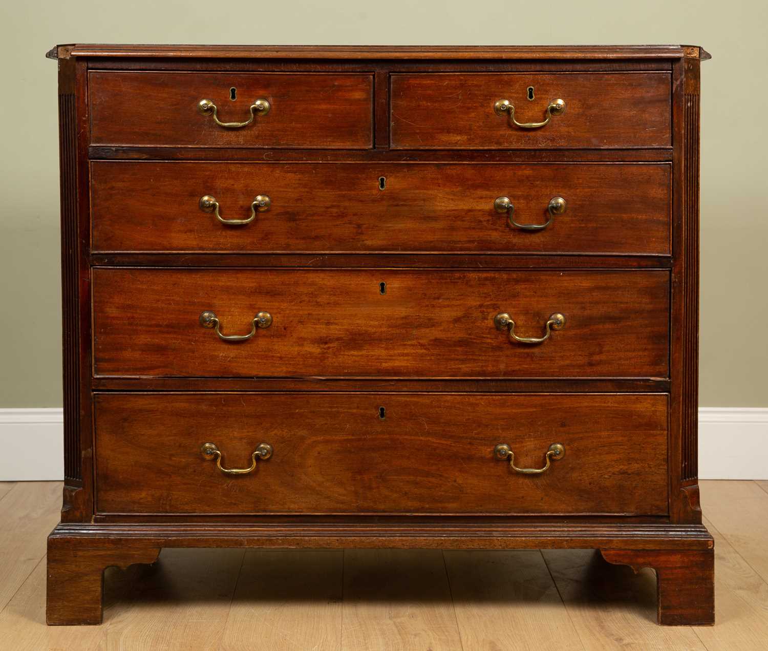 A George III mahogany chest of two short and three long drawers with brass swan neck handles and