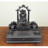 A 19th century ebony Anglo-Indian desk stand carved with elephants with a watch stand rule and
