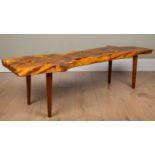 In the style of George Nakashima, a rustic yew wood coffee table of plank form on tapering legs,