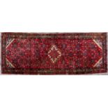 A modern red ground tribal rug with central white stepped diamond within the dense foliate field and