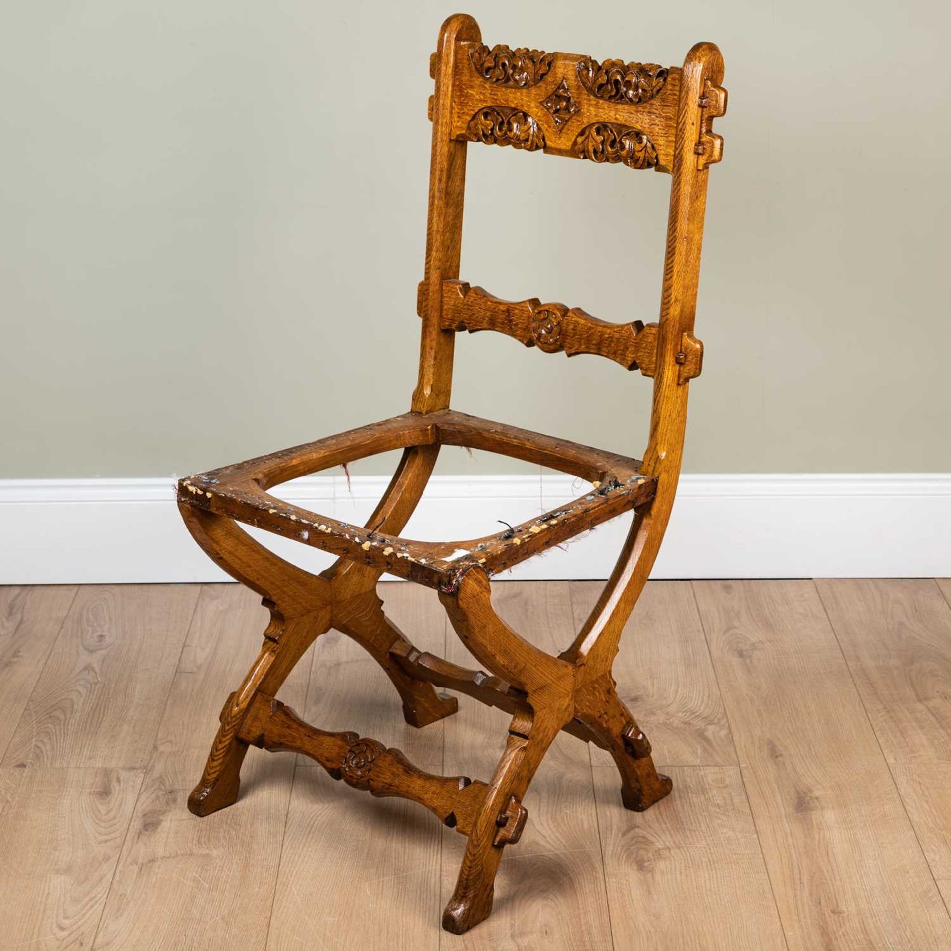 A Victorian oak side chair in the manner of Pugin with pegged carved bar back and X frame supports