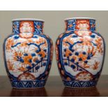 A pair of late 19th/early 20th century Japanese Imari vases decorated with landscape cartouche