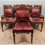 A set of eight Victorian walnut dining chairs with carved cresting rails, overstuffed red leather
