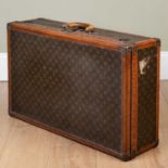 A vintage Louis Vuitton suitcase, early 20th century, with leather carrying handle, the lock