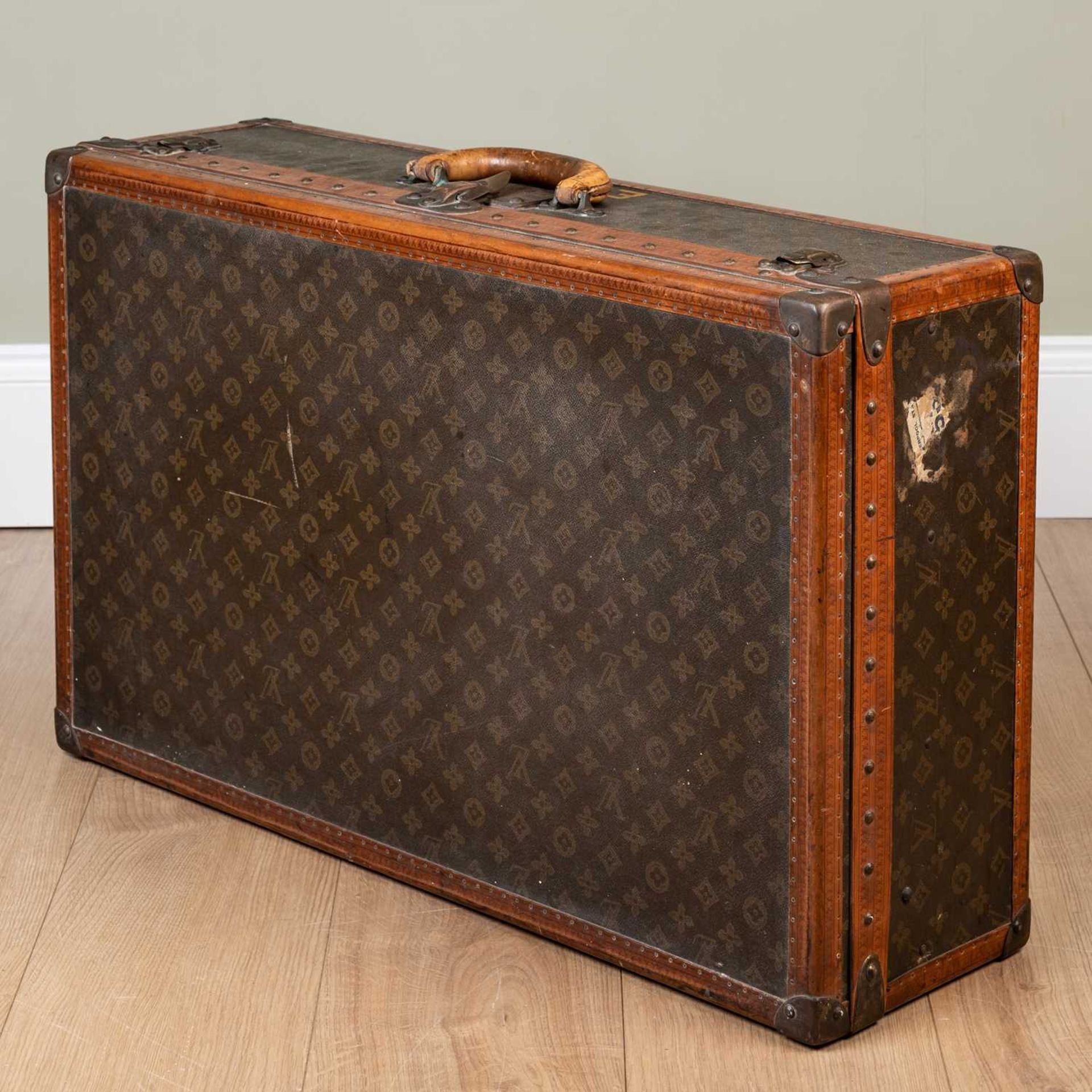 A vintage Louis Vuitton suitcase, early 20th century, with leather carrying handle, the lock