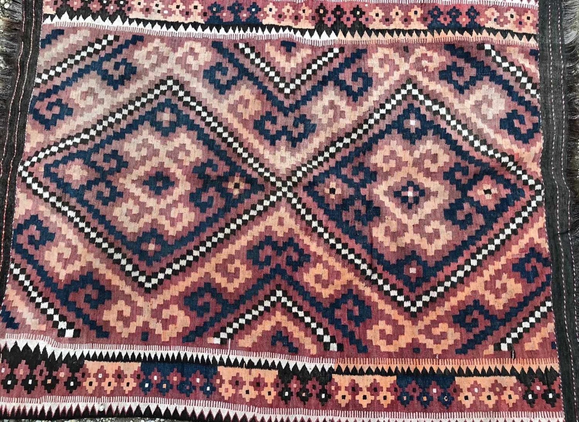 A 20th century Kelim rug with rust-brown, cream and blue decoration, with fringed edges, unlabelled,