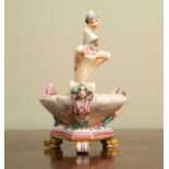A decorative porcelain ornament, possibly Royal Worcester, depicting a fairy perched on top of an