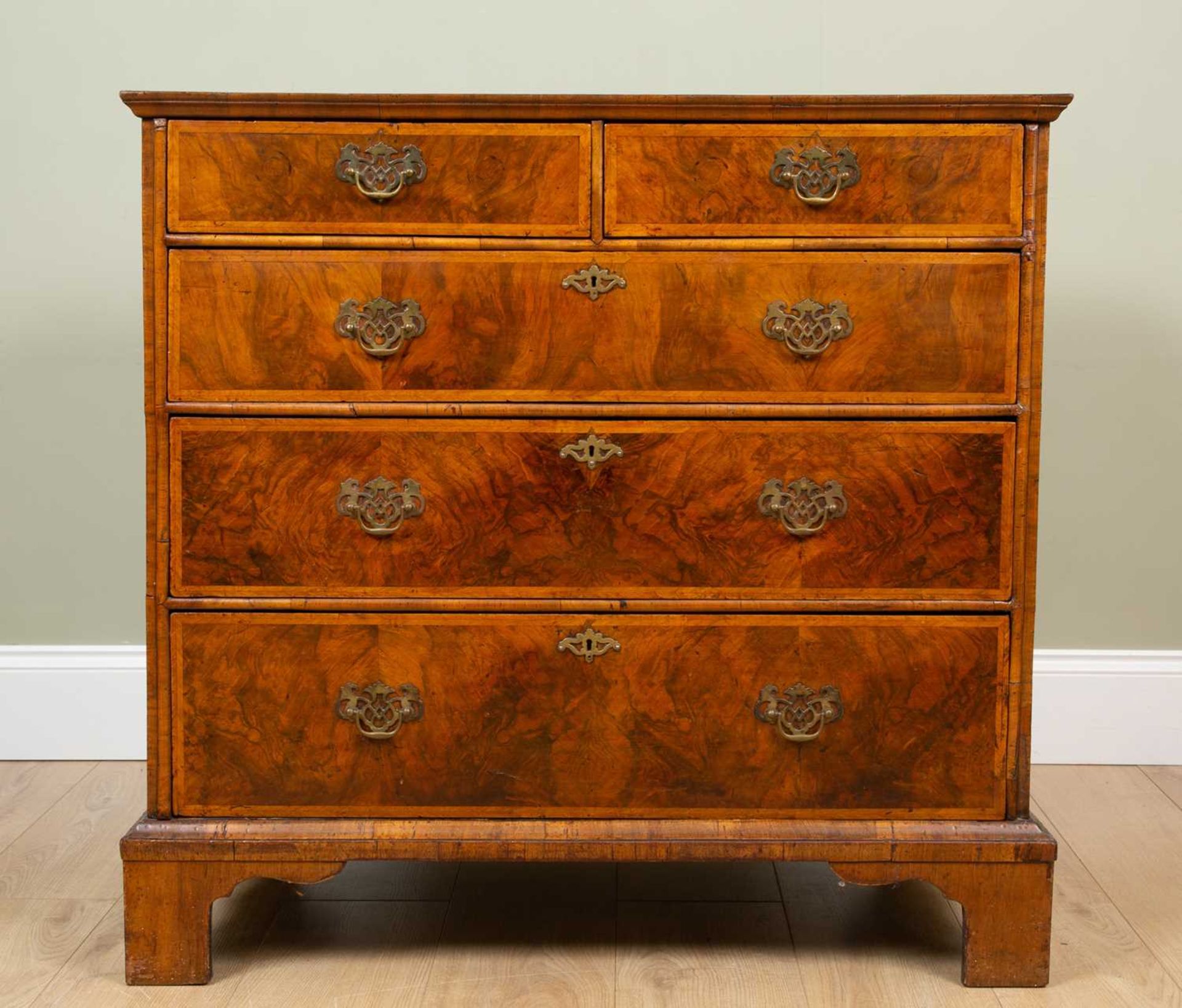 A George II walnut chest of two short and three long drawers standing on bracket feet, the quartered