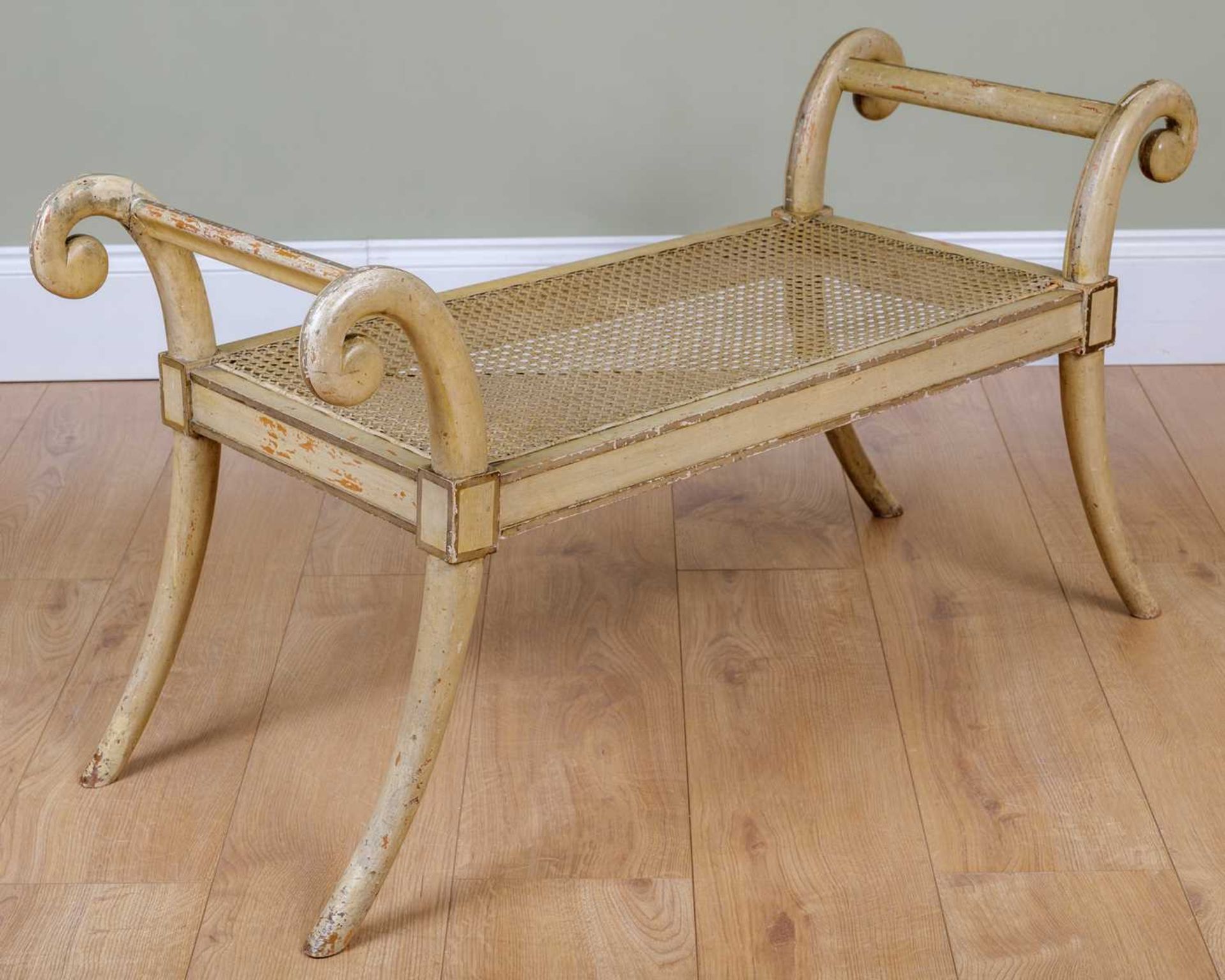 A painted window seat with scrolling ends and caned seat, 100cm wide, 39cm high x 53.5cm highIn
