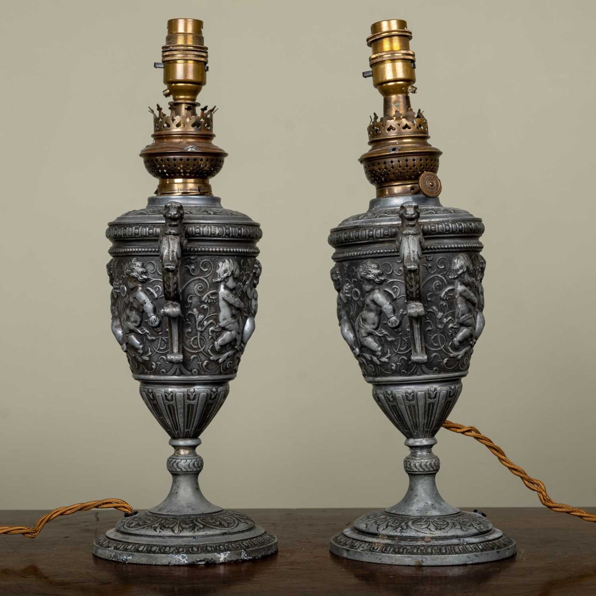 A pair of continental spelter oil lamps of vase form, decorated with putti, later converted for - Image 2 of 2