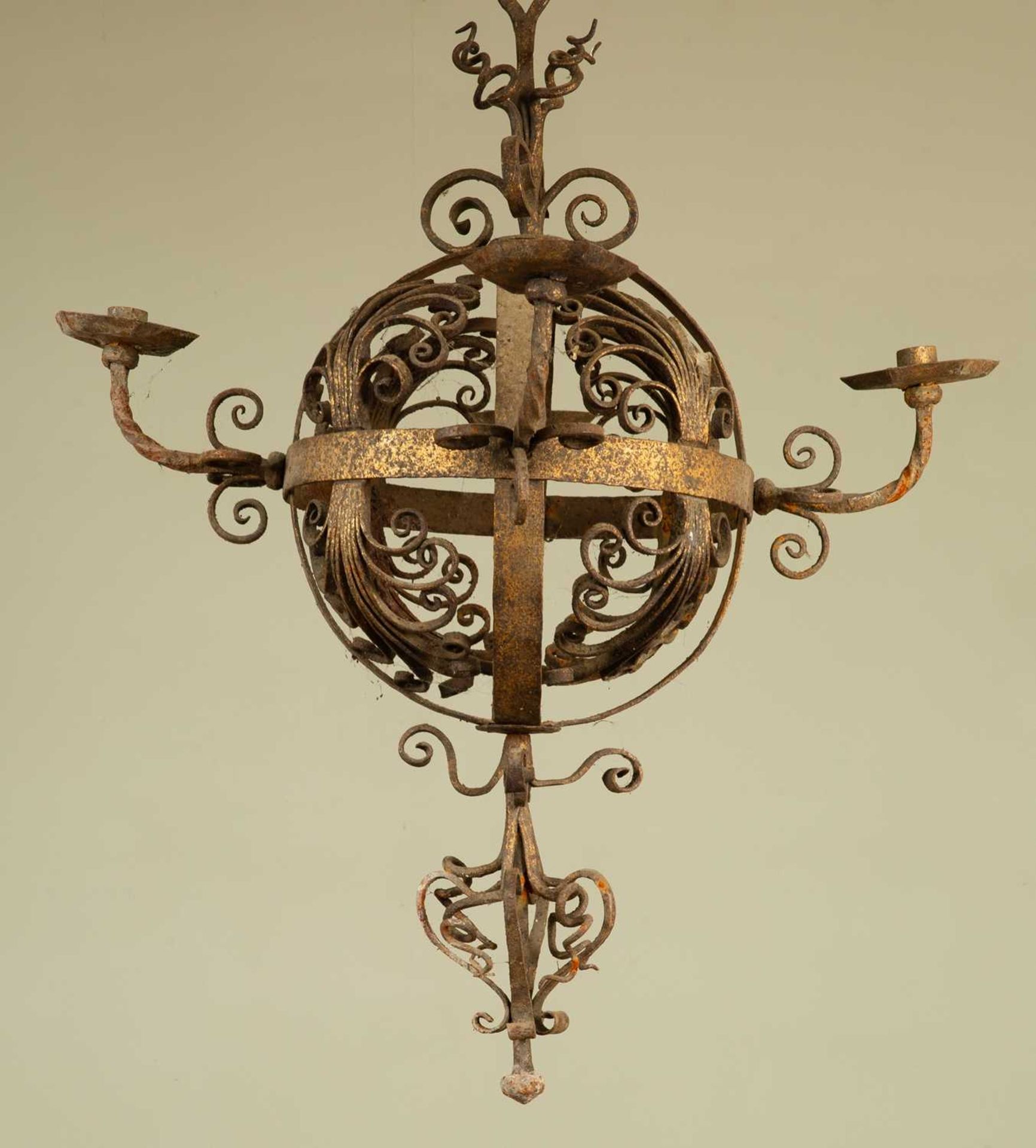 An early 20th century wrought iron hanging chandelier, the central globe with four branches and