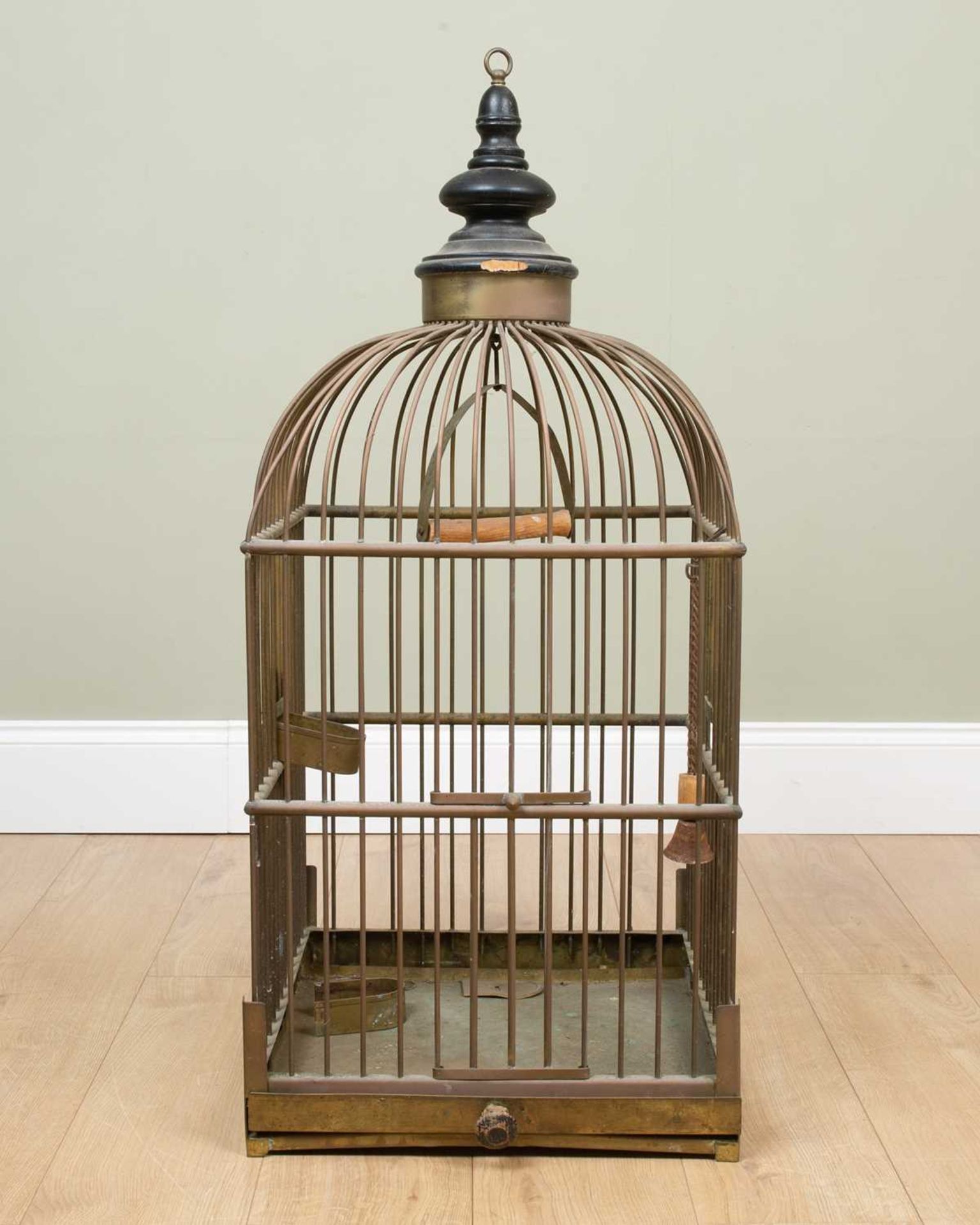 A Victorian brass bird cage of square section, with black painted turned finial, a sliding tray to