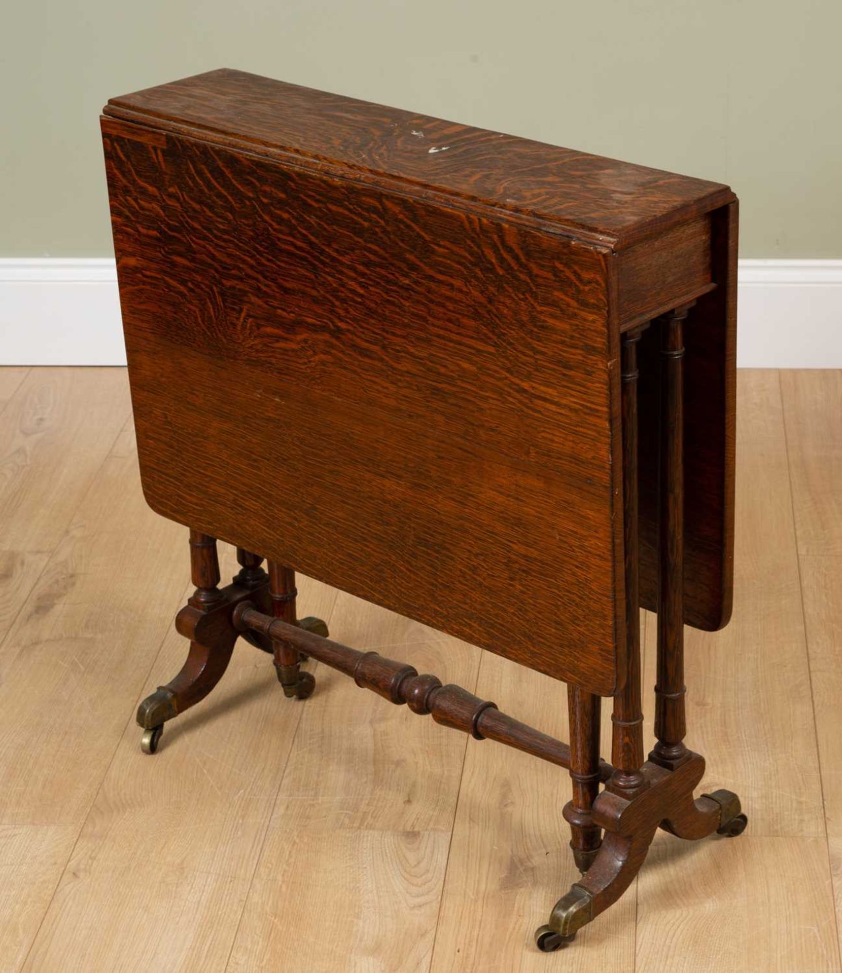 A Victorian oak Sutherland table with turned tapering legs and turned supports terminating in