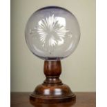 A Victorian star cut glass sphere on a turned wooden stand, possibly originally a shop display in