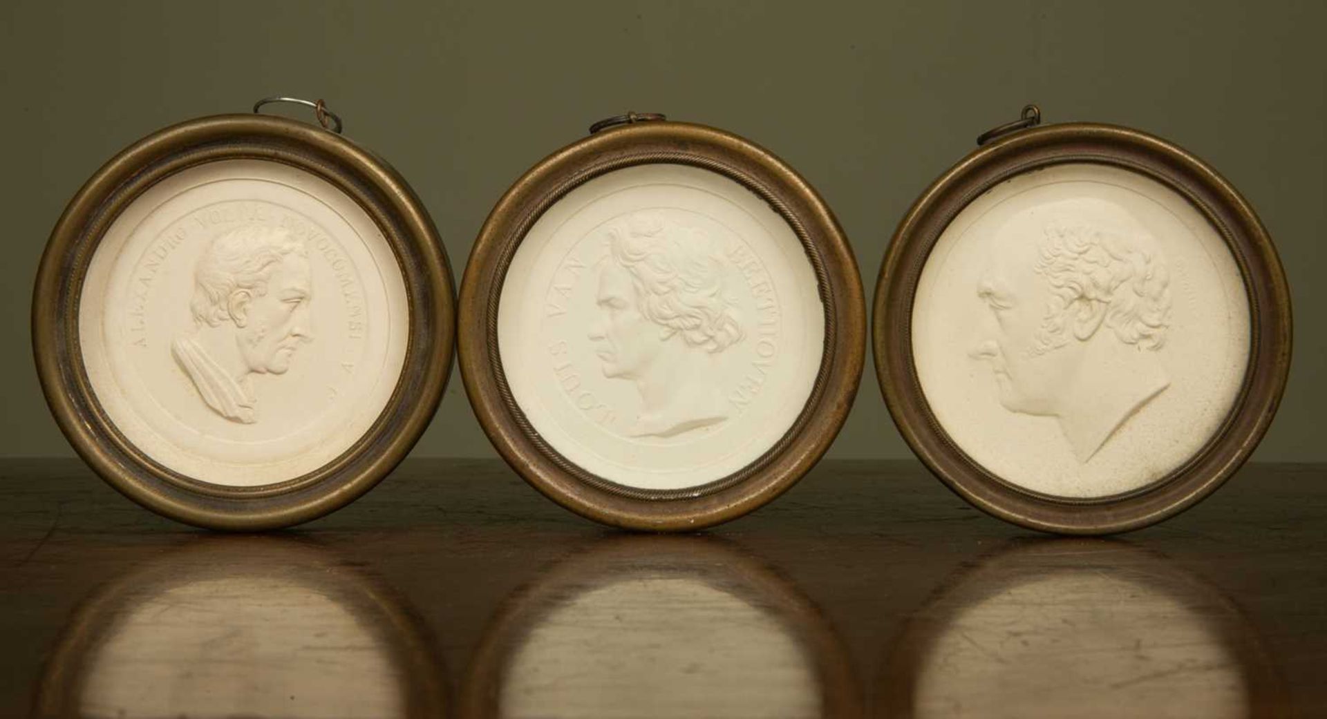 A group of three German circular plaster roundels of notable figures, set in brass frames and with