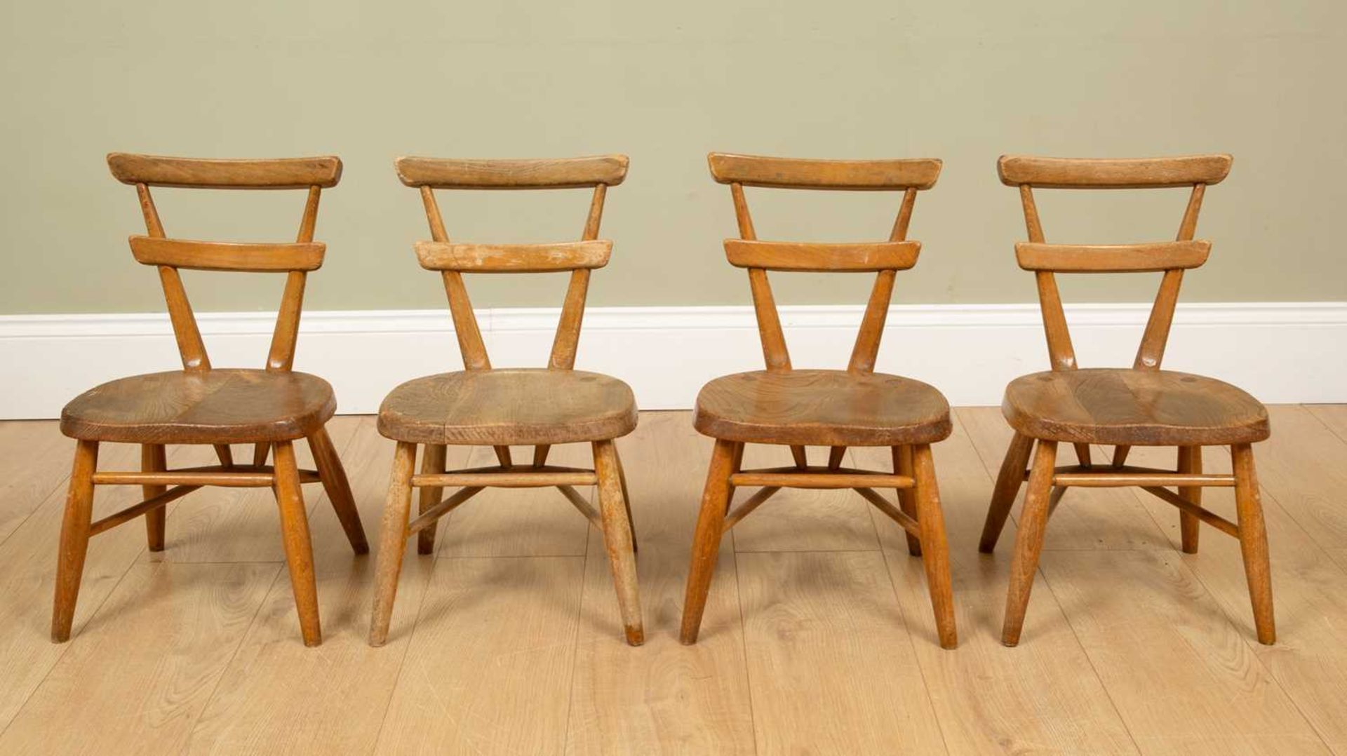 A set of four child-sized Ercol light elm chairs with blank cartouche dots to the reverse,