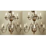 A pair of Dutch-style two-tier twelve-light brass chandeliers with scrolling branches, each