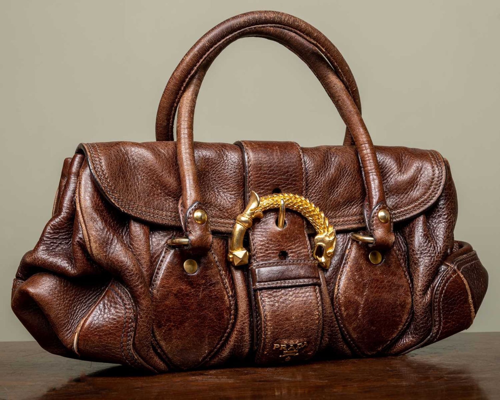 A ladies Prada Cervo dragon buckle brown leather bag with additional brown leather tags and