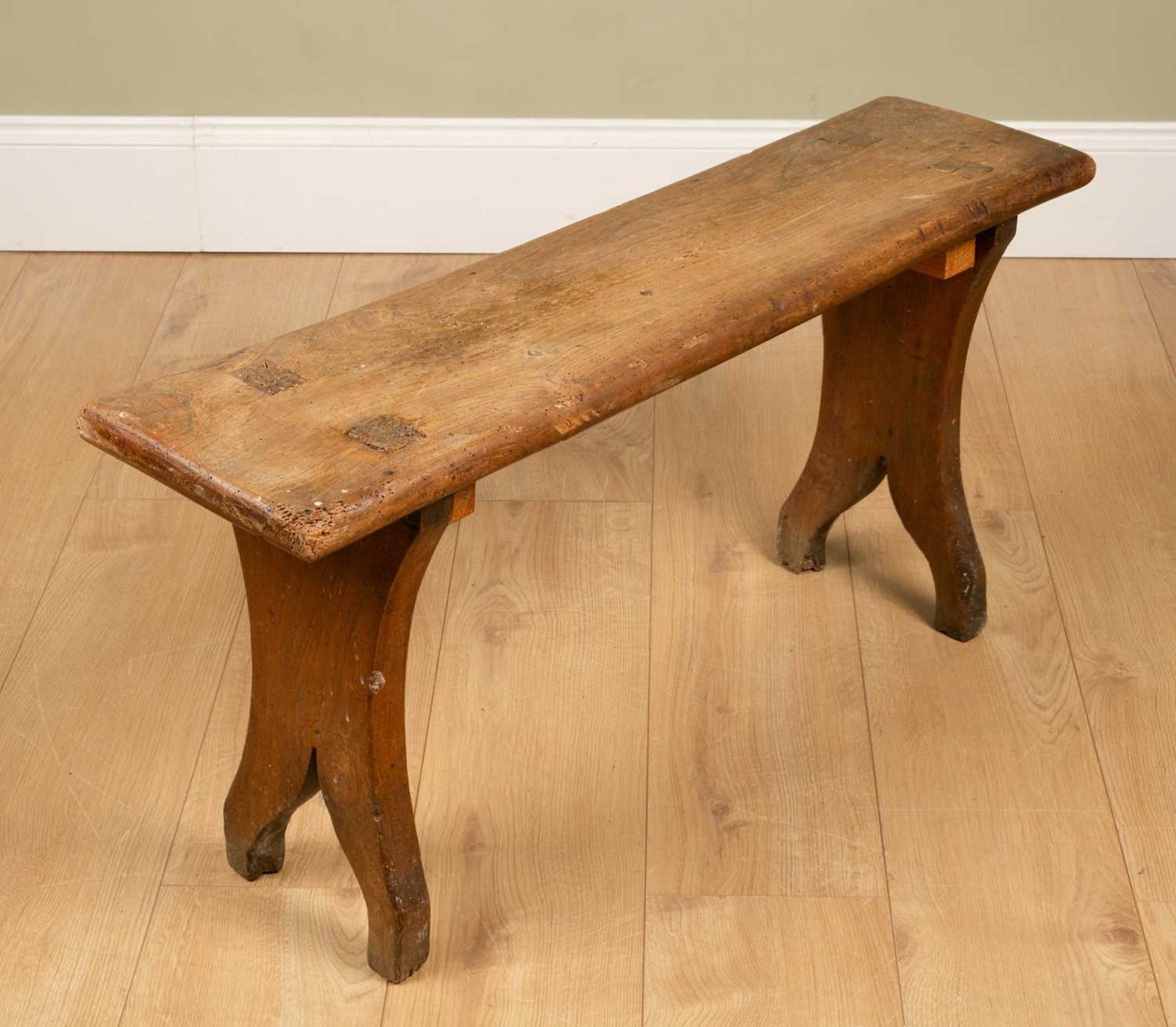 A small elm bench with shaped waisted ends, 95cm wide x 24cm deep x 44cm highMinor marks, dents