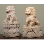 Two similar carved stone dogs of foe on decorative plinth bases, the larger 33cm high (2)Minor