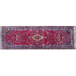 An Oriental red ground runner with floral scrolls within a triple banded border, 320cm x