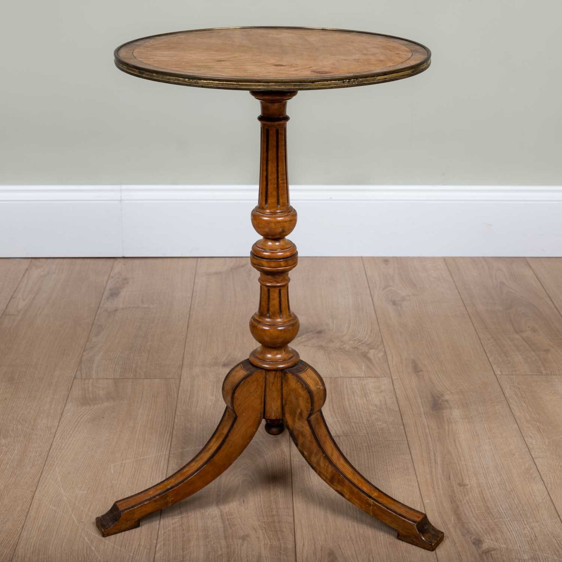 A satinwood circular tripod table with brass edging to the top and decorative inlay to the
