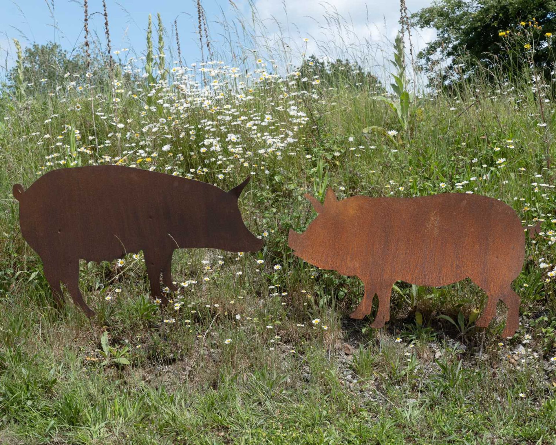 A pair of pig silhouette garden ornaments, the largest 118cm wide, 68.5cm high not including the
