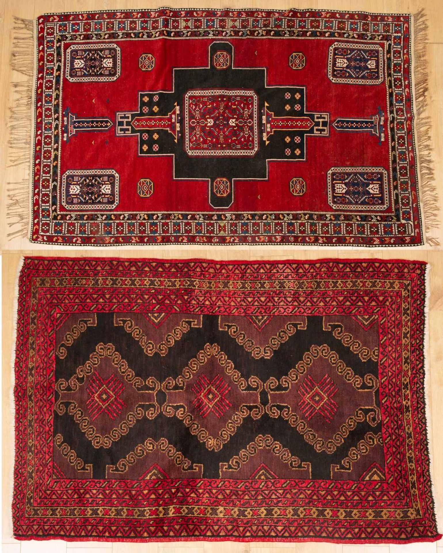 An antique red ground rug with central black ground motif and within a triple banded border, 228cm x