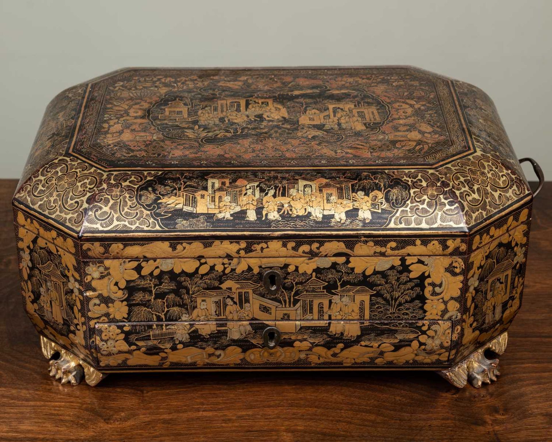 An antique Chinese lacquered work box with canted corners and carrying handles to the side, the