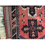 A red ground tribal runner with six cross designs to the central field, 304cm long x 75cm wide;