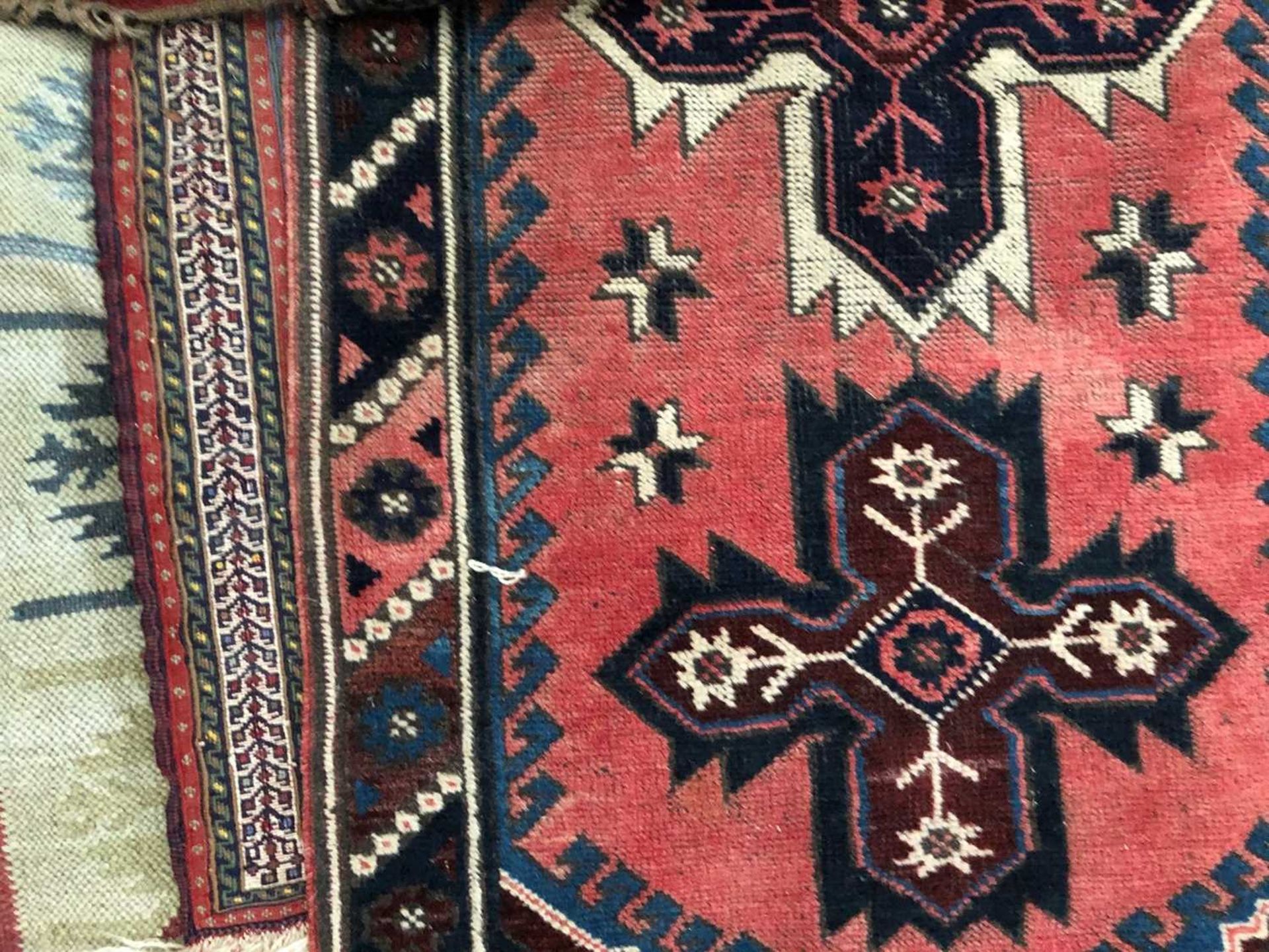 A red ground tribal runner with six cross designs to the central field, 304cm long x 75cm wide;