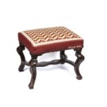 An 18th century mahogany footstool with later woolwork upholstery and cabriole legs united by a