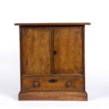 A 19th century fruitwood apprentice table cabinet, having a pair of doors above a long drawer, on