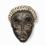 An African tribal Dan mask, decorated with cowrie shells, Ivory Coast, 30cm x 25 cm