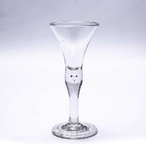 A mid 18th century English wine glass with a bell shaped bowl, a waisted stem and a plain foot,