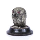 A late 19th century silver plated novelty owl inkwell with glass eyes and ebonised pine base, the