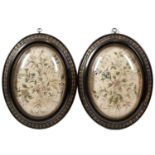 A pair of early 19th century oval raised silk embroidered floral pictures each mounted in convex