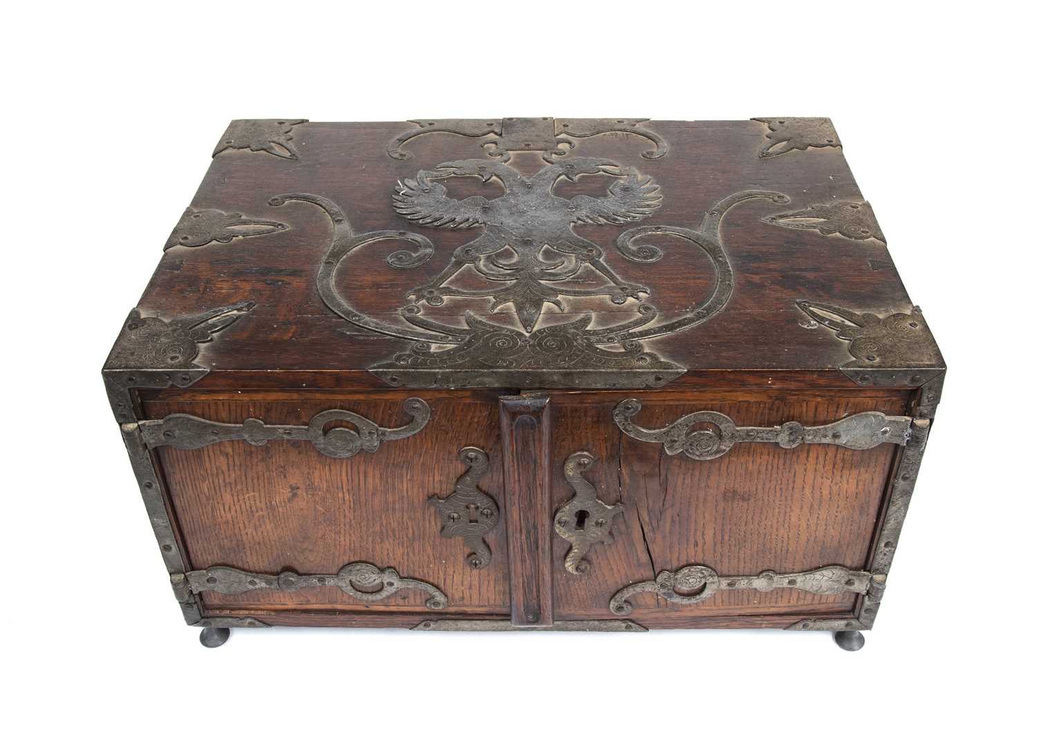 A 17th century German oak and metal bound table top cabinet of drawers, having a double headed eagle